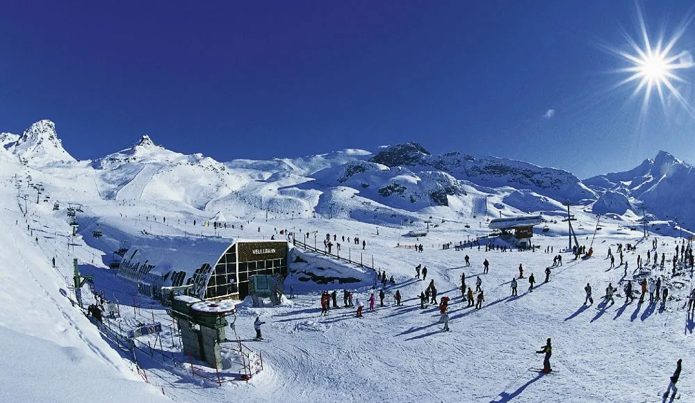 Talstation einer Bergbahn mit vielen Skifahrern unter strahlender Sonne – Skiurlaub im Hochgebirge