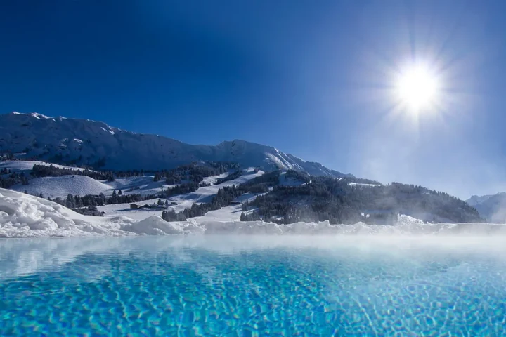 Dampfender Außenpool mit Blick auf verschneite Berge und Sonne – Wellness im Skiurlaub